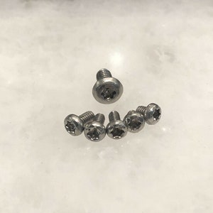 May include: Six silver-toned screws with a star-shaped head.