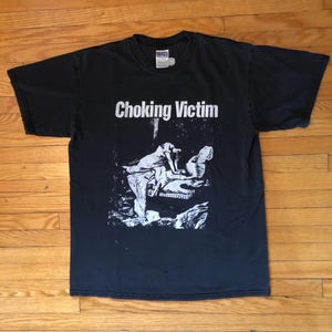 May include: Black t-shirt with a white graphic print of a band called "Choking Victim".