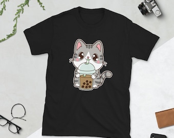 May include: Black t-shirt featuring a cartoon illustration of a grey and white cat drinking bubble tea.