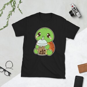 May include: Black t-shirt with a cartoon illustration of a green turtle wearing a brown shell and holding a brown boba tea with a green straw.
