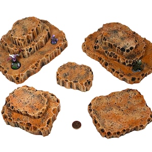 Puede incluir: Conjunto de seis formaciones rocosas texturizadas de color marrón y tostado para juegos de mesa. Las rocas son de varios tamaños y formas, algunas con plataformas elevadas.