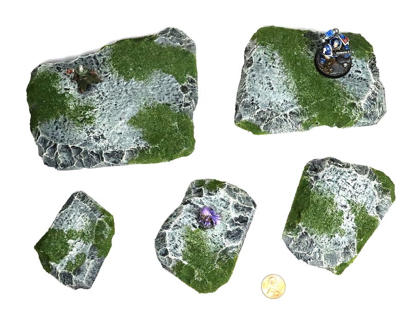 May include: Five different sized, gray and green, rocky terrain pieces for tabletop gaming. The pieces are made of foam and have a realistic texture.