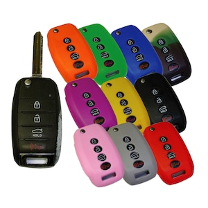 May include: Assortment of colorful silicone key covers for car keys. The covers are in various colors, including orange, green, blue, brown, purple, yellow, black, pink, gray, and red. The covers have four buttons and the word "HOLD" printed on them.