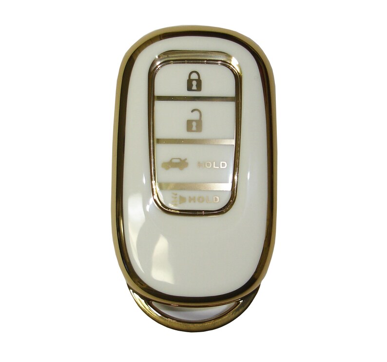 May include: A white car key fob with a gold trim. The key fob has four buttons: lock, unlock, trunk, and panic. The buttons are labeled with icons. The key fob also has a gold ring.