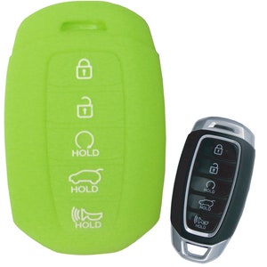 Puede incluir: Funda de silicona verde para llavero con botones blancos etiquetados como "HOLD" para una llave de coche con un mando a distancia negro. El mando a distancia tiene detalles plateados y botones etiquetados como "HOLD".