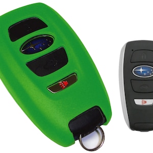 May include: Two car key fobs. One is bright green with black buttons and a silver Subaru emblem. The other is black with silver trim and a Subaru emblem. Both have keyless entry buttons.