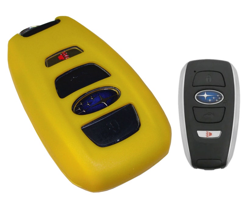 May include: Yellow silicone key fob cover for a Subaru car key. The cover has four buttons and a Subaru logo. The key fob is black with a silver trim and a Subaru logo.