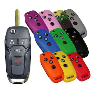May include: A collection of car key fobs in various colors, including black, gray, pink, purple, blue, green, orange, yellow, and red. The keys have buttons for locking, unlocking, and other functions. The main key is black with a metal key blade.