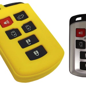 May include: A yellow silicone key fob cover with six buttons. The buttons are black with white symbols. The key fob cover is designed to protect a car key fob.