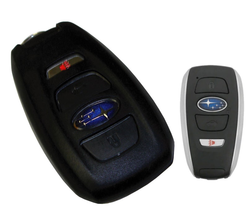 May include: Two black car key fobs with a silver Subaru logo and buttons for lock, unlock, trunk, and panic. The key fob on the left has a red LED light.
