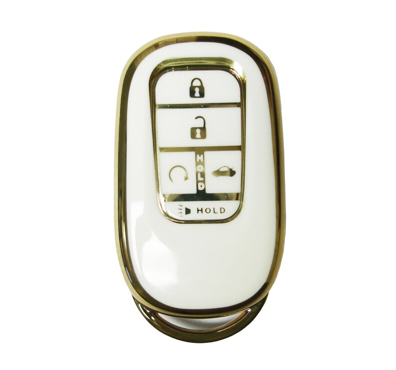 May include: A white car key fob with a gold trim. The key fob has five buttons: lock, unlock, trunk release, panic, and hold.