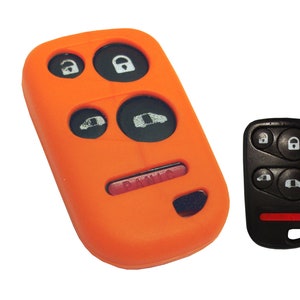 May include: An orange car key fob cover and a black car key fob. The orange cover has four black buttons with white icons and a red "PANIC" button. The black key fob has four buttons with white icons and a red button.
