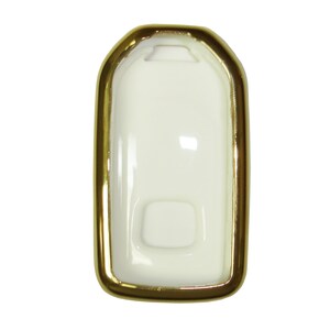 May include: A white key fob case with a gold trim. The case has a rectangular shape with rounded corners.