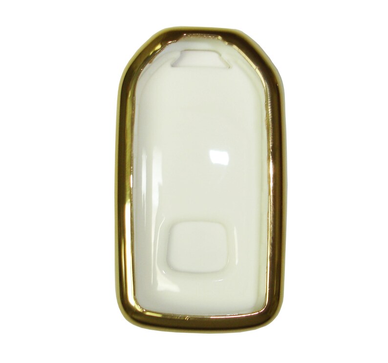 May include: A white key fob case with a gold trim. The case has a rectangular shape with rounded corners.