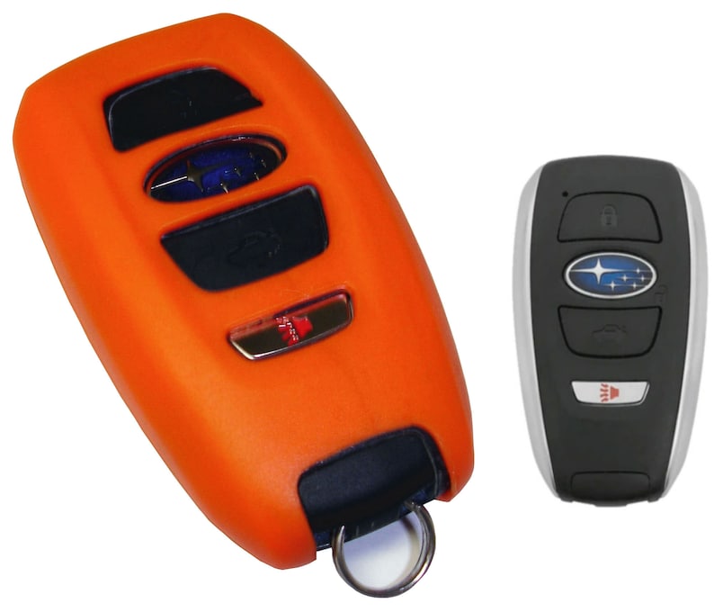 May include: Orange silicone key fob cover for a Subaru car key. The key fob has four buttons and a Subaru logo. The key fob is attached to a silver key ring.
