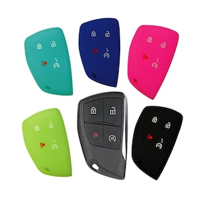 May include: A collection of car key fobs in various colors, including teal, blue, pink, green, black, and gray. Each key fob has buttons for locking, unlocking, and other functions. The keys are displayed against a white background.