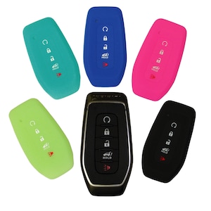 May include: Six silicone key covers in different colors: green, blue, pink, black, and two shades of green. The covers are designed to fit a car key fob with five buttons, including a "HOLD" button.
