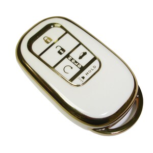 May include: White car key fob with a gold trim. The key fob has five buttons: lock, unlock, trunk, panic, and hold.