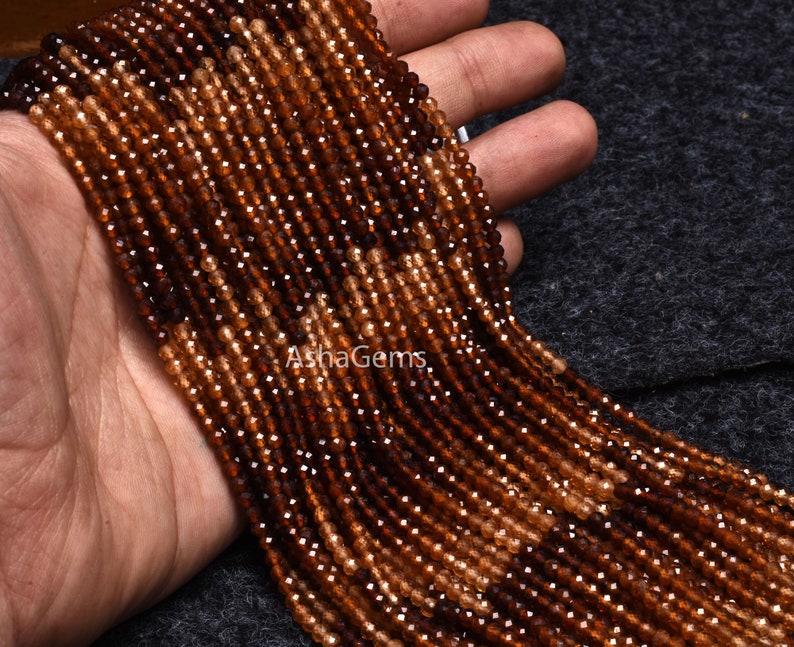 May include: A strand of brown and orange gemstone beads. The beads are faceted and have a slightly irregular shape. The beads are strung on a clear thread and are approximately 4mm in diameter.