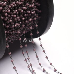May include: A spool of black chain with light purple faceted beads. The chain is strung with small, round beads that are evenly spaced.
