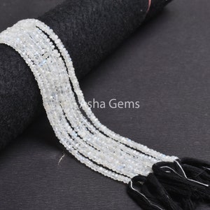 May include: A strand of white moonstone beads with black tassels. The beads are small and round, and the tassels are made of a soft, silky material.