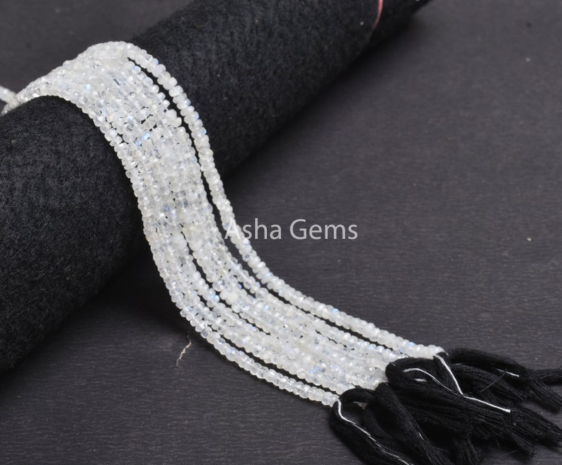 May include: A strand of white moonstone beads with black tassels. The beads are small and round, and the tassels are made of a soft, silky material.