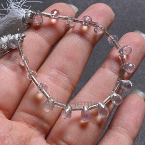 May include: A strand of faceted clear and light pink teardrop shaped gemstone beads strung on silver spacer beads.