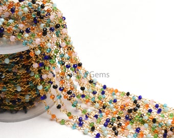 May include: A gold chain with colorful beads, including blue, green, pink, orange, and black. The chain is wound around a spool.