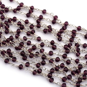 May include: A strand of silver chain with small, faceted, amethyst-colored beads.