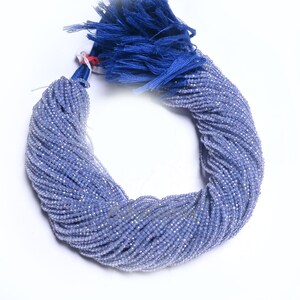 Puede incluir: Una hebra de cuentas de piedras preciosas facetadas de color azul claro. Las cuentas son peque&ntilde;as y redondas, y est&aacute;n enhebradas en un hilo fino. Las cuentas est&aacute;n dispuestas en una espiral suelta, y est&aacute;n atadas con un borla azul.
