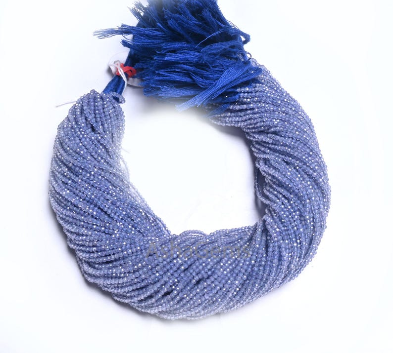 Puede incluir: Una hebra de cuentas de piedras preciosas facetadas de color azul claro. Las cuentas son peque&ntilde;as y redondas, y est&aacute;n enhebradas en un hilo fino. Las cuentas est&aacute;n dispuestas en una espiral suelta, y est&aacute;n atadas con un borla azul.