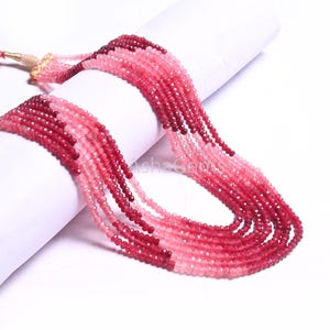 May include: A strand of pink and red gemstone beads. The beads are faceted and have a graduated colour from light pink to dark red.