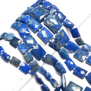 Puede incluir: Una hebra de cuentas de lapislázuli facetadas de color azul intenso con motas blancas y doradas. Las cuentas son de forma rectangular y tienen un acabado pulido.