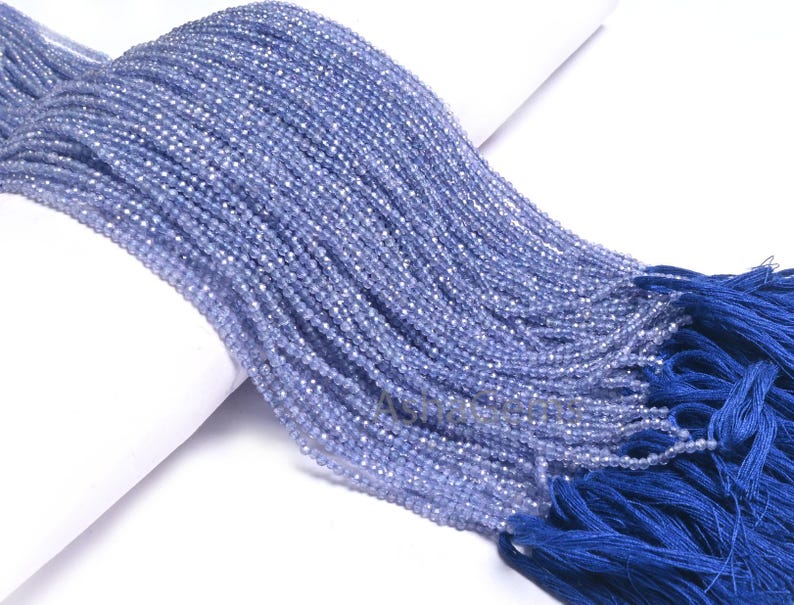 Puede incluir: Una hebra de cuentas de piedras preciosas de color azul claro con un borla azul. Las cuentas son peque&ntilde;as y redondas, y la borla est&aacute; hecha de un material suave y sedoso.