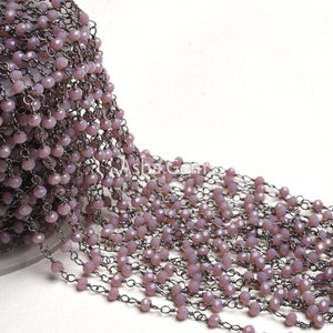 May include: A close-up of a long strand of light purple faceted beads strung on a silver chain. The beads are small and uniform in size, and the chain is delicate and intricate.