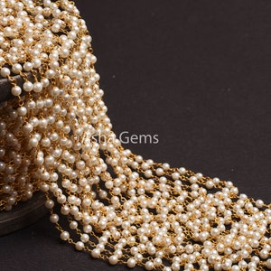 May include: A spool of white pearl and gold chain, a type of jewelry making supply.
