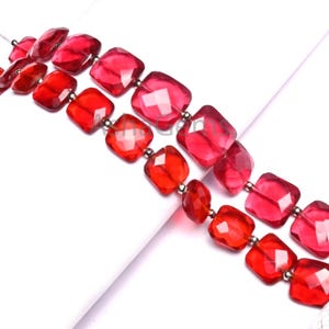 May include: Two strands of faceted, square-cut beads in shades of red and pink. The beads are strung on a thin, clear cord with small silver-colored spacer beads. The beads have a polished, translucent appearance.