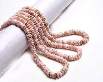 Pode incluir: Um fio de contas de concha rosa e branca, com um formato ligeiramente irregular, dispostas em uma espiral solta sobre uma superfície branca.