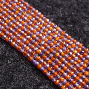 Könnte beinhalten: Eine Strähne aus facettierten Glasperlen in Lila und Orange. Die Perlen sind in einem sich wiederholenden Muster angeordnet, wobei zwei lila Perlen von zwei orangefarbenen Perlen gefolgt werden.