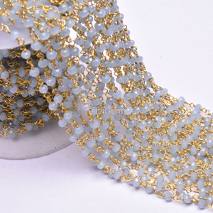 Puede incluir: Una hebra de cuentas de piedras preciosas azul claro con eslabones de cadena dorados. Las cuentas son facetadas y tienen un brillo sutil. La cadena es delicada y tiene un acabado pulido.