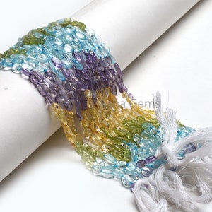 Può includere: Un filo di perle di pietre preziose in vari colori, tra cui azzurro, viola, verde e giallo. Le perle sono di forma ovale e hanno una finitura liscia e lucida.