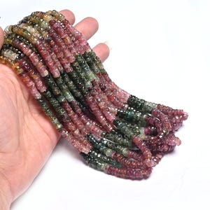 Puede incluir: Una hebra de cuentas de piedras preciosas multicolores. Las cuentas son una mezcla de rosa, verde y negro. Las cuentas son facetadas y tienen un acabado liso y pulido.