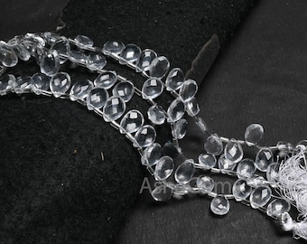May include: Strands of clear, faceted teardrop-shaped beads. The beads are strung together with silver-colored wire, creating a delicate and elegant appearance. The beads are displayed against a dark background.