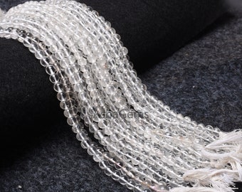 May include: A strand of clear quartz beads, each bead is round and smooth. The beads are strung on a white cord and have a white tassel at the end.