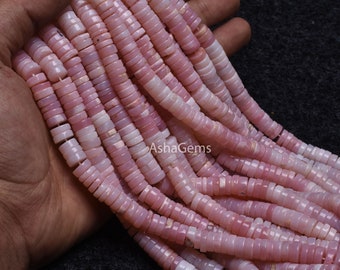 Pode incluir: Um fio de contas de opala rosa, cada conta é um disco redondo e plano com uma forma ligeiramente irregular. As contas são enfiadas em um fio transparente.