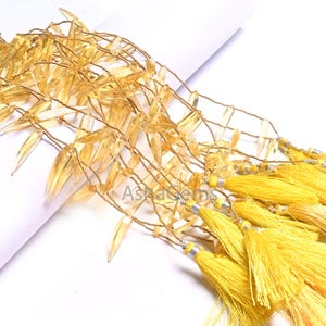 May include: A strand of golden yellow faceted crystal beads strung on wire with small yellow tassels hanging from the bottom.