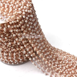 Könnte beinhalten: Eine Spule mit weißer Perlen- und Roségoldkette. Die Kette besteht aus kleinen, runden Perlen und Roségolddraht.