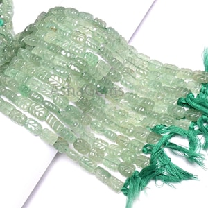 Puede incluir: Hilos de cuentas de piedras preciosas verde claro con tallas de hojas. Las cuentas están ensartadas con hilo verde, formando un conjunto. Las cuentas translúcidas y las tallas de hojas añaden detalle a las piedras preciosas.