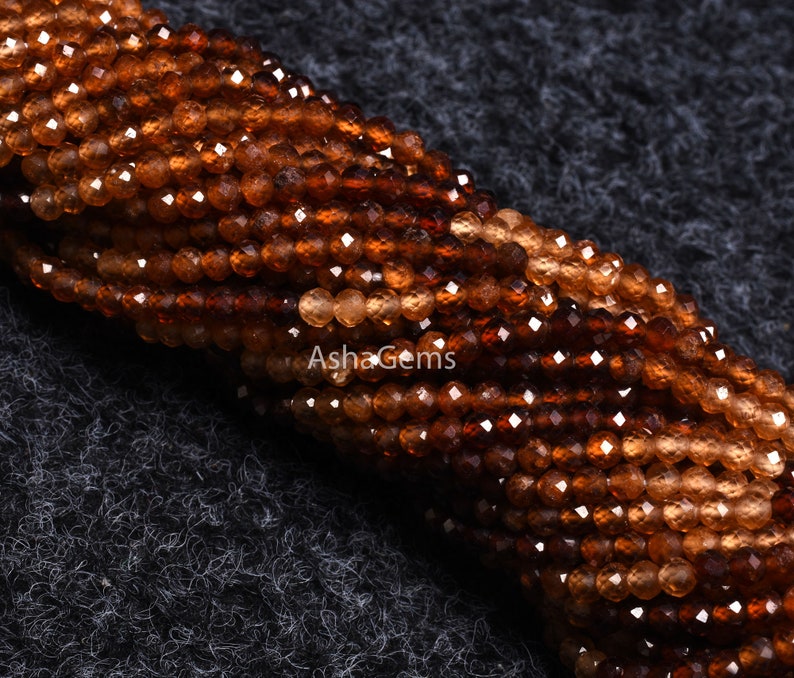 May include: A strand of brown faceted gemstone beads. The beads are small and round, and they have a shiny, polished finish.