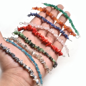 Puede incluir: Un conjunto de ocho pulseras de chips de piedras preciosas, cada una con un color diferente: gris, azul, blanco, rojo, verde, naranja y marrón. Las pulseras están hechas con pequeñas piedras preciosas irregulares y están enhebradas en alambre de plata.